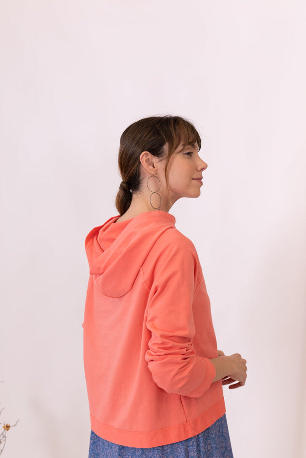 MODELO DE ESPALDAS CON SUDADERA CORAL CAPUCHA