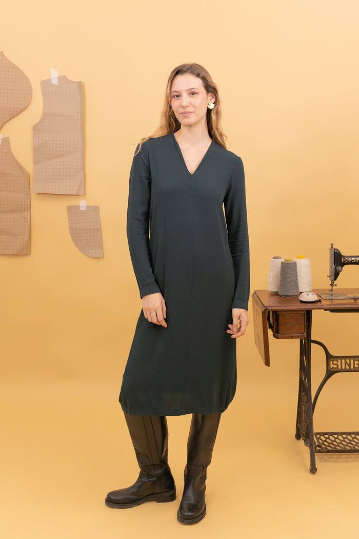 Vestido midi Spirit de Poems BCN en verde Botella, con escote pico y manga larga, vista frontal sobre modelo